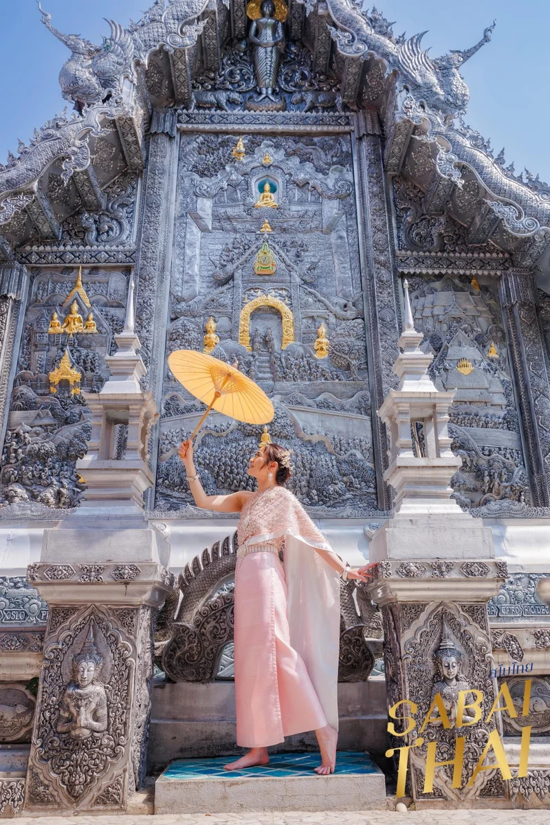 Woman in pink Thai Sabai dress with umbrella at silver temple — Sabai Thai Dressing